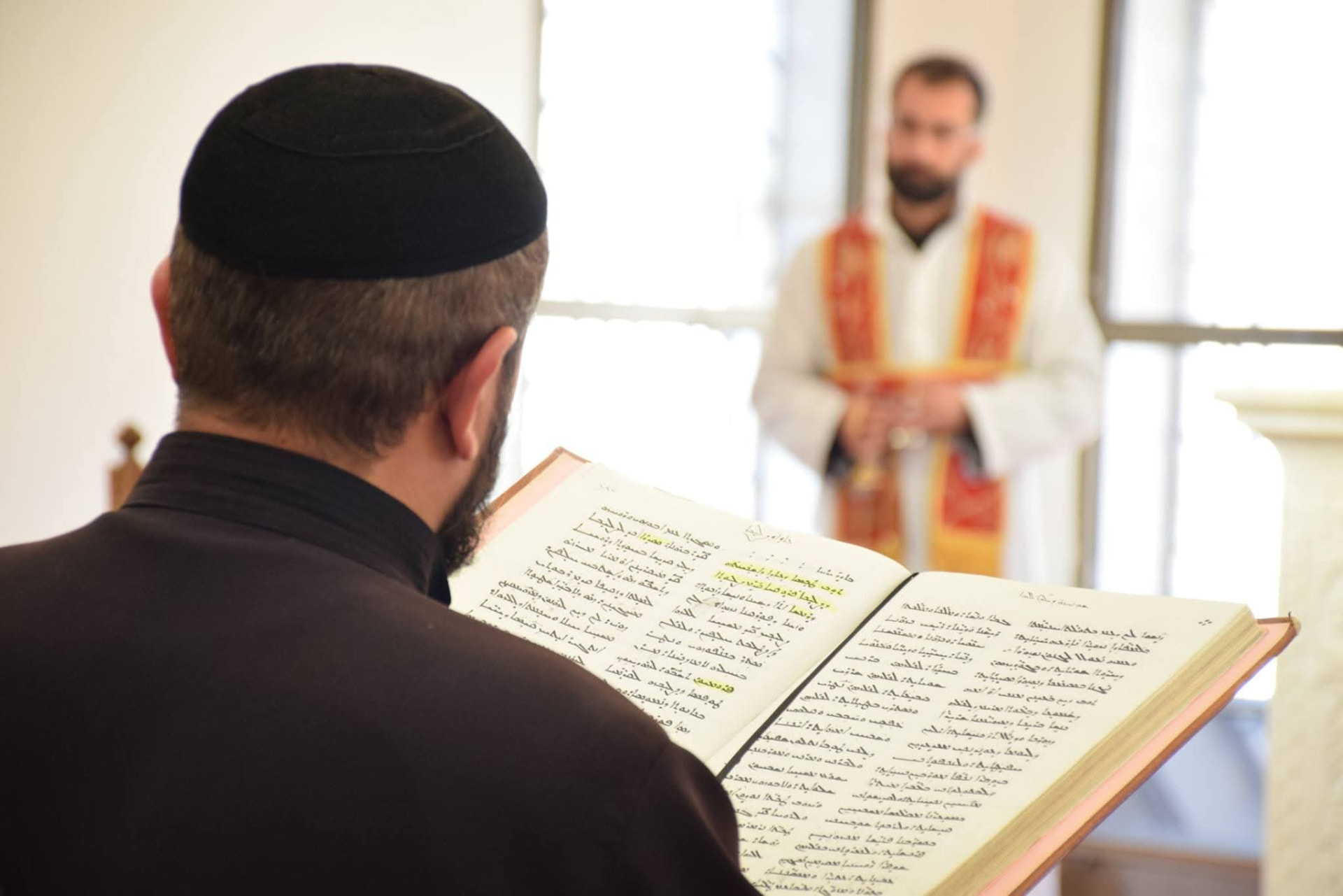 Seminarian following the Syriac liturgy from a service book